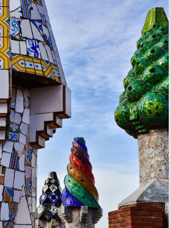 A wide-angle photo of Park Guell with Gaudi's mosaic art in the foreground.
