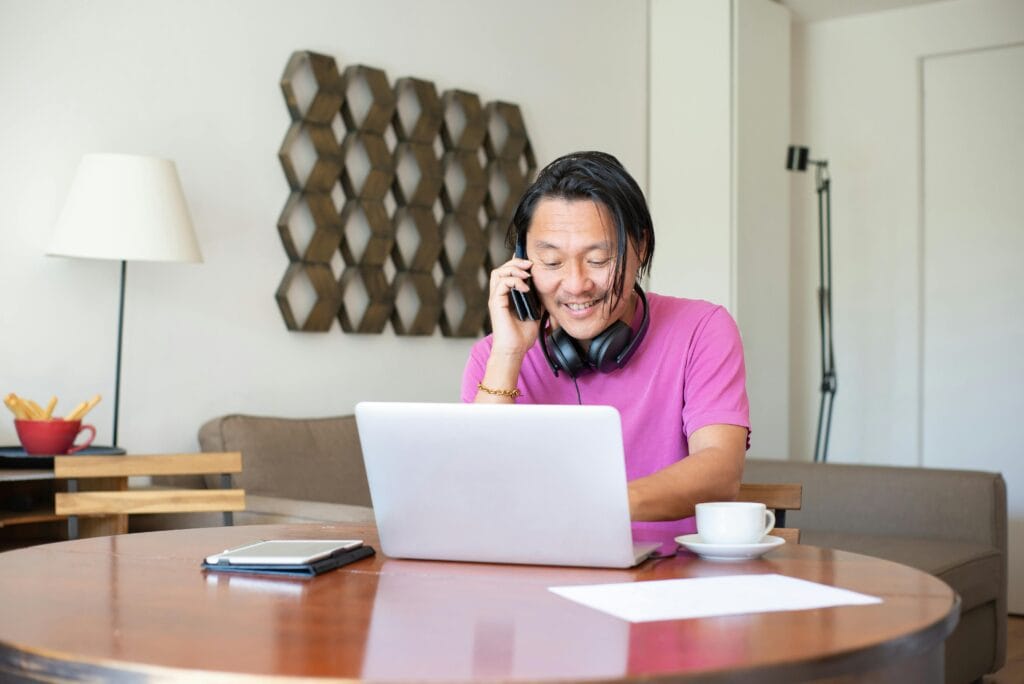 A young freelancer working on a laptop, creating a Fiverr gig in a cozy home workspace with a cup of coffee and sticky notes around.