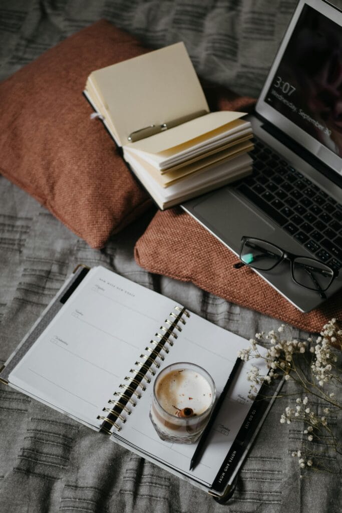 Cozy home setup with a laptop playing an English movie, a notebook on vocabulary, and a cup of coffee.