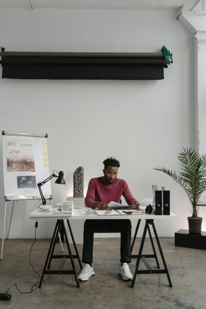 A young creative graphic designer working on a branding project from a laptop in a modern home studio, surrounded by design sketches and coffee